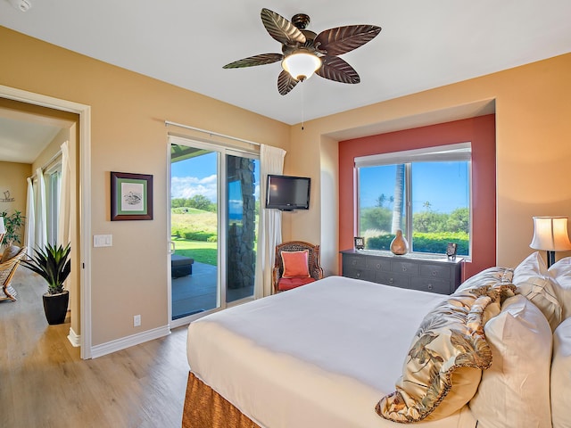 bedroom featuring access to outside, multiple windows, light wood-style floors, and baseboards