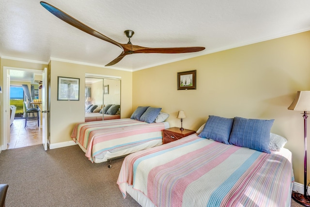 carpeted bedroom with a closet, baseboards, and ornamental molding