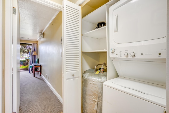 clothes washing area with baseboards, carpet flooring, laundry area, a textured ceiling, and stacked washer / drying machine