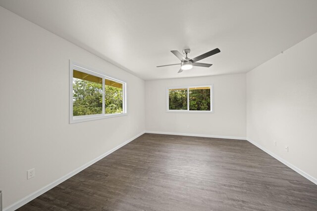 empty room with dark wood-style flooring, ceiling fan, and baseboards