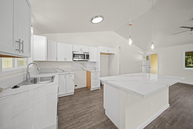 kitchen featuring light stone countertops, dark wood-type flooring, a sink, a center island, and stainless steel microwave