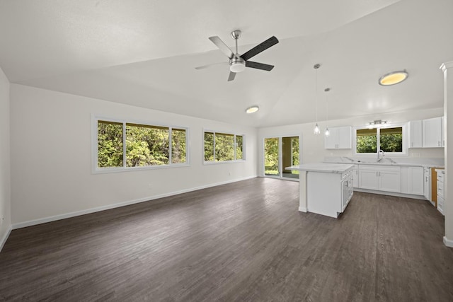 interior space featuring dark wood-style floors, a center island, light countertops, open floor plan, and vaulted ceiling