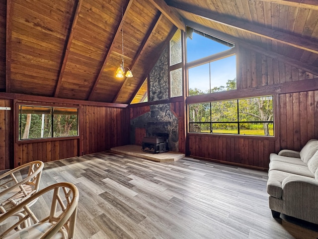 living area with wood ceiling, a wood stove, wood walls, and beamed ceiling