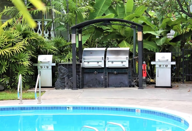 outdoor pool featuring area for grilling, an outdoor kitchen, and fence