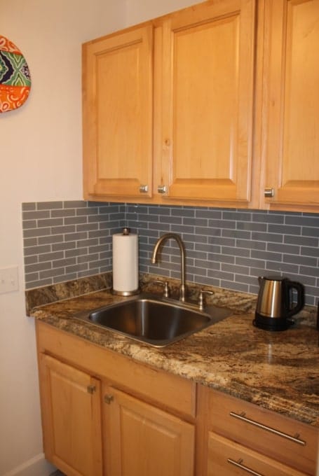 kitchen with a sink, decorative backsplash, dark stone countertops, and light brown cabinetry