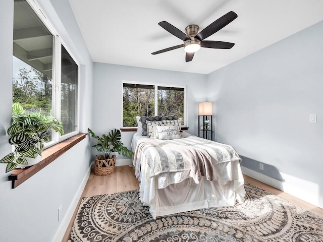 bedroom featuring a ceiling fan, baseboards, and wood finished floors