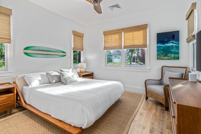 bedroom with light wood-style floors, visible vents, baseboards, and a ceiling fan