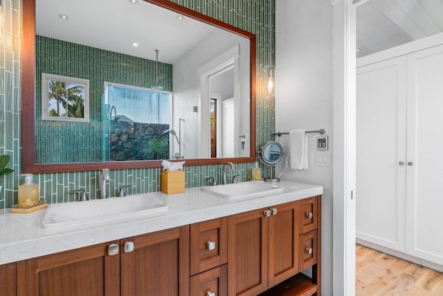 bathroom featuring double vanity, a walk in shower, a sink, and wood finished floors