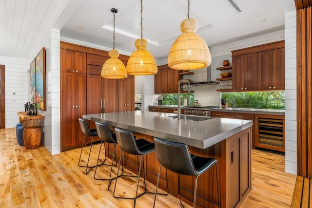 kitchen featuring decorative light fixtures, visible vents, light wood-style floors, beverage cooler, and a kitchen breakfast bar