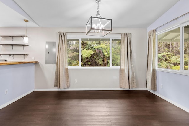 unfurnished dining area featuring a chandelier, wood finished floors, electric panel, and baseboards