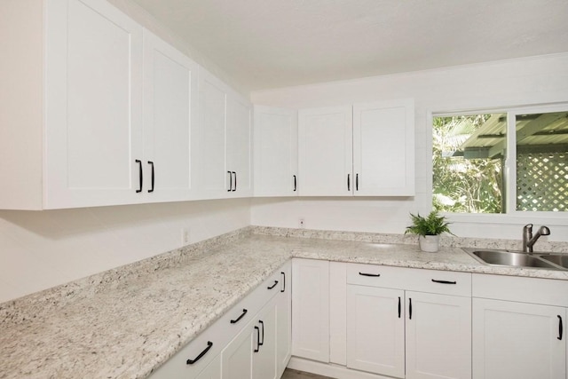 kitchen featuring white cabinets, light stone countertops, and a sink