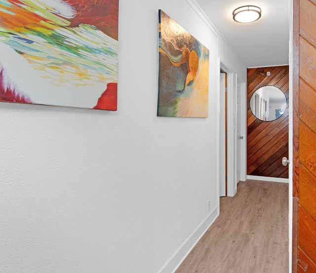 hallway featuring wooden walls, baseboards, and wood finished floors