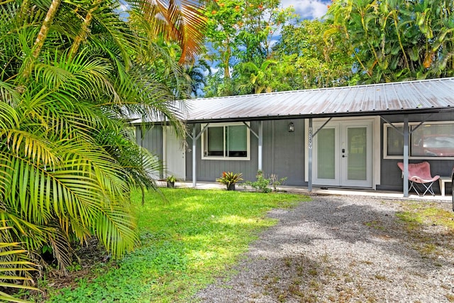 view of front of property featuring french doors, metal roof, and a front yard