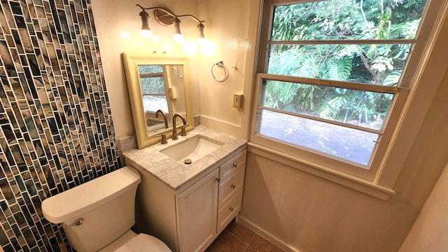 half bath featuring vanity, plenty of natural light, tile patterned flooring, and toilet