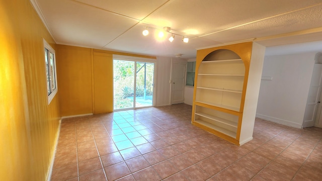 spare room featuring crown molding, light tile patterned floors, baseboards, and built in features