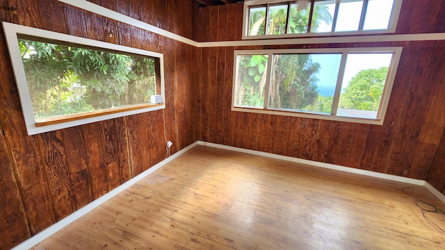 unfurnished room featuring wooden walls, baseboards, and wood finished floors