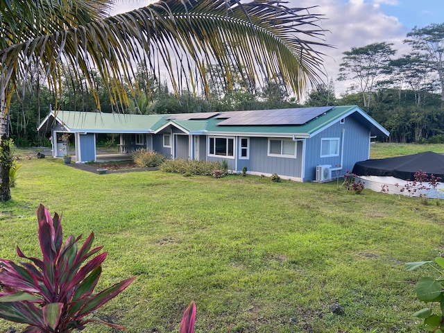 ranch-style house with ac unit, roof mounted solar panels, and a front lawn