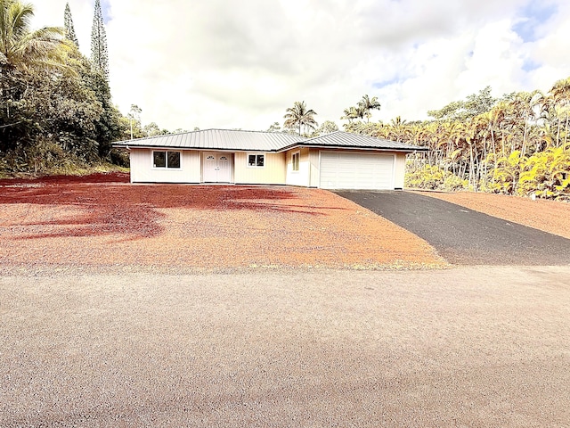 single story home with a garage, metal roof, and driveway