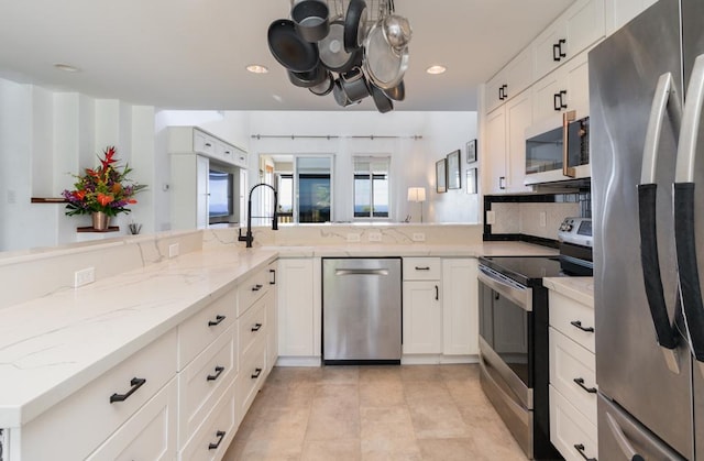 kitchen featuring light stone counters, recessed lighting, stainless steel appliances, a sink, and white cabinetry