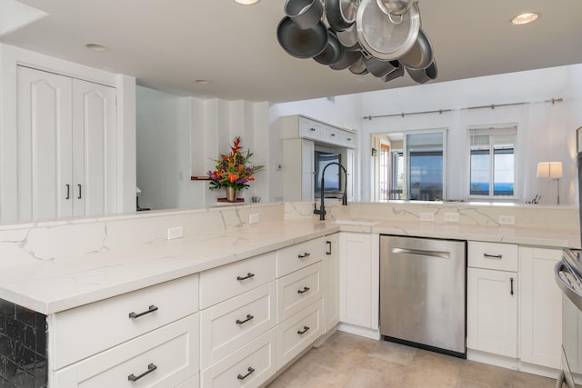 kitchen with light stone counters, white cabinets, dishwasher, and a sink