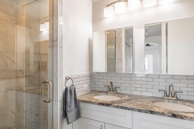 bathroom with double vanity, a stall shower, a sink, and backsplash