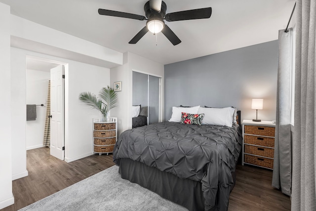 bedroom with a ceiling fan, wood finished floors, baseboards, a closet, and ensuite bathroom