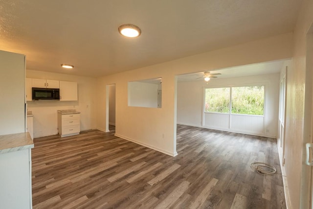 interior space with baseboards, a ceiling fan, and dark wood-type flooring