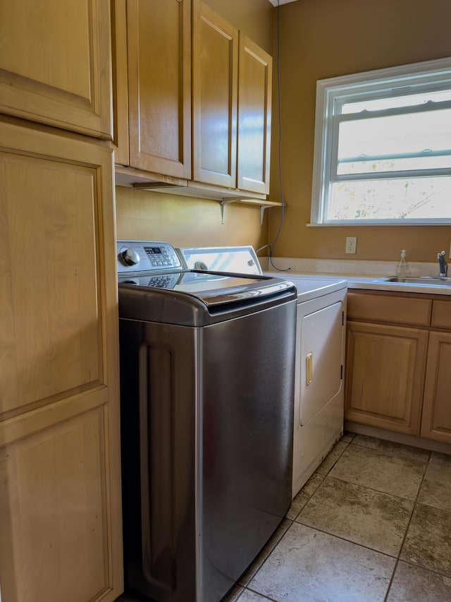 washroom featuring washing machine and dryer, cabinet space, and a sink