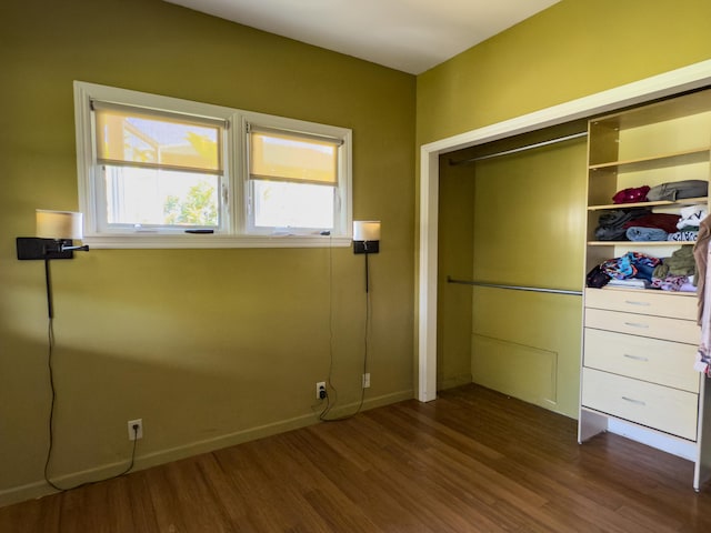 unfurnished bedroom with a closet, baseboards, and dark wood-type flooring