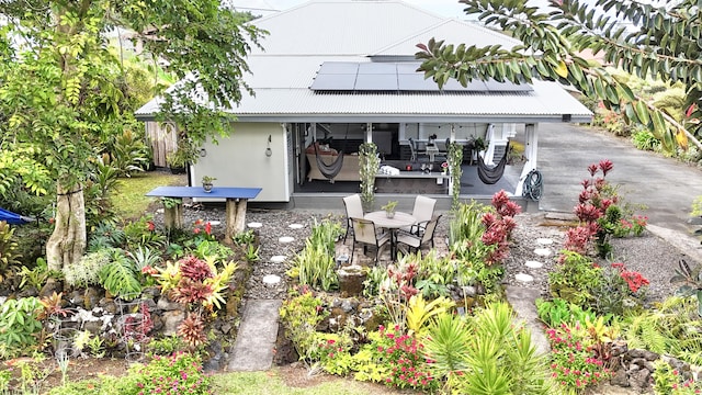 rear view of house featuring roof mounted solar panels