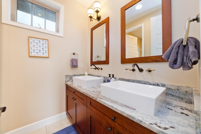 bathroom with baseboards, marble finish floor, double vanity, and a sink