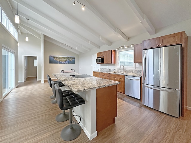 kitchen with stainless steel appliances, brown cabinets, light wood-style flooring, and a center island