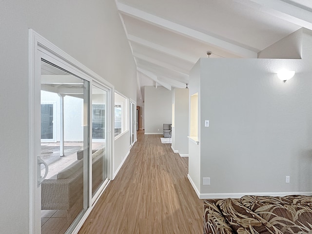 corridor featuring light wood-style flooring, vaulted ceiling with beams, and baseboards