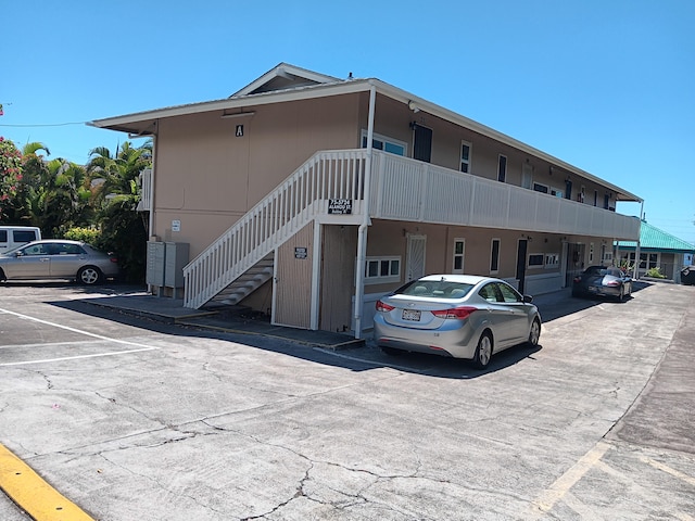 view of property featuring stairway and uncovered parking