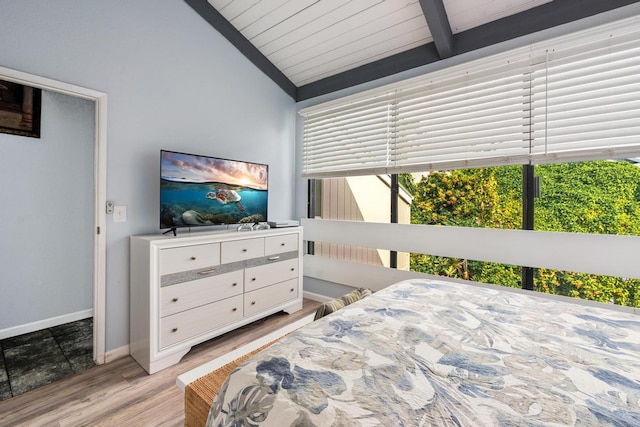 bedroom featuring baseboards, vaulted ceiling with beams, and light wood-style floors