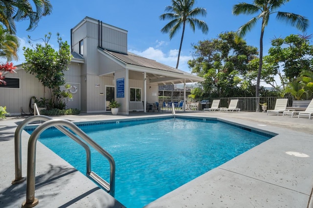 community pool with a patio area and fence