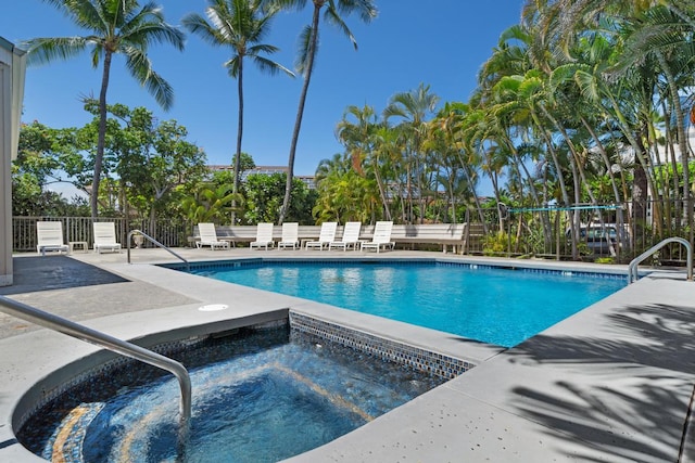 pool featuring a patio area, a community hot tub, and fence