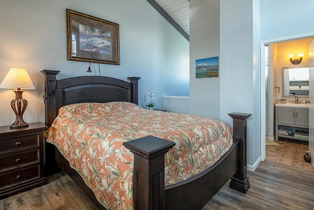 bedroom featuring a sink, connected bathroom, and dark wood-style flooring