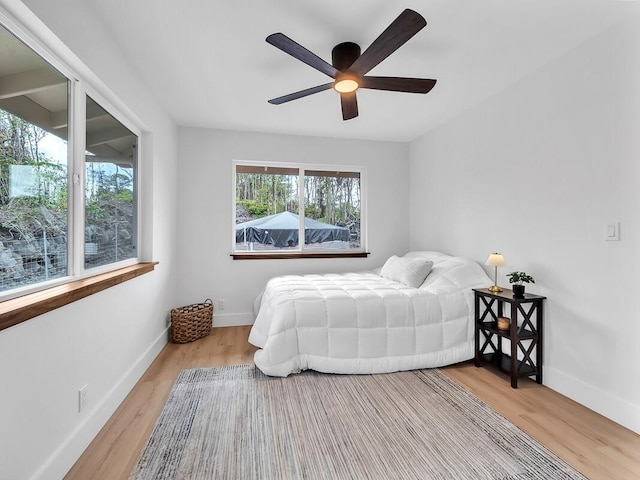 bedroom with ceiling fan, baseboards, and wood finished floors