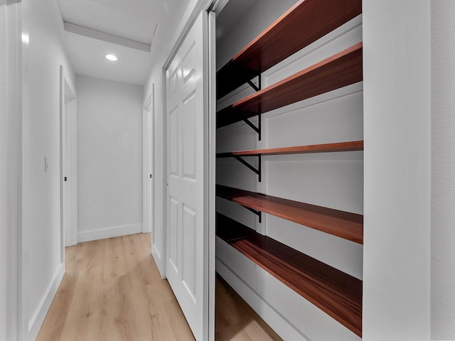 hallway featuring light wood finished floors, recessed lighting, attic access, and baseboards