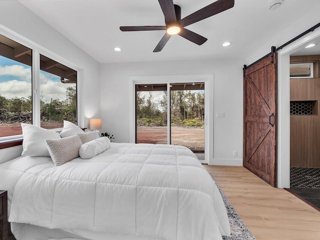 bedroom with access to exterior, recessed lighting, light wood finished floors, and a barn door