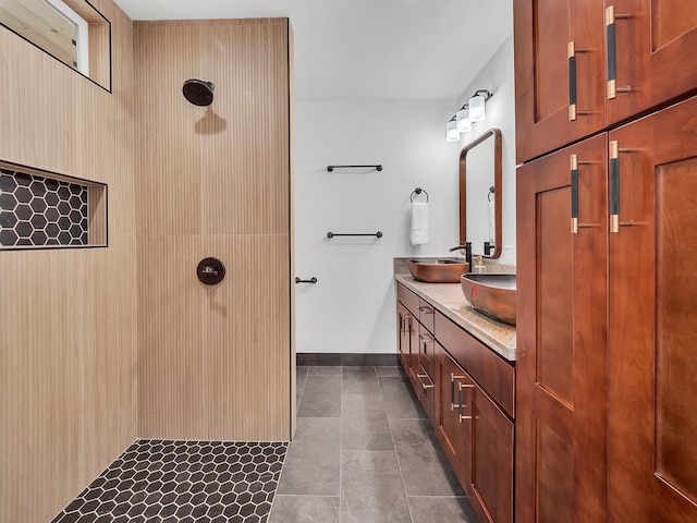 full bath with a sink, baseboards, tiled shower, tile patterned floors, and double vanity