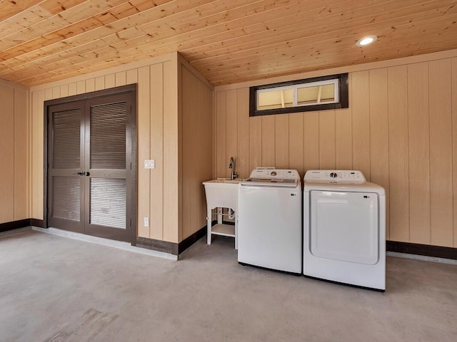 clothes washing area featuring wood ceiling, a sink, washer and dryer, laundry area, and baseboards