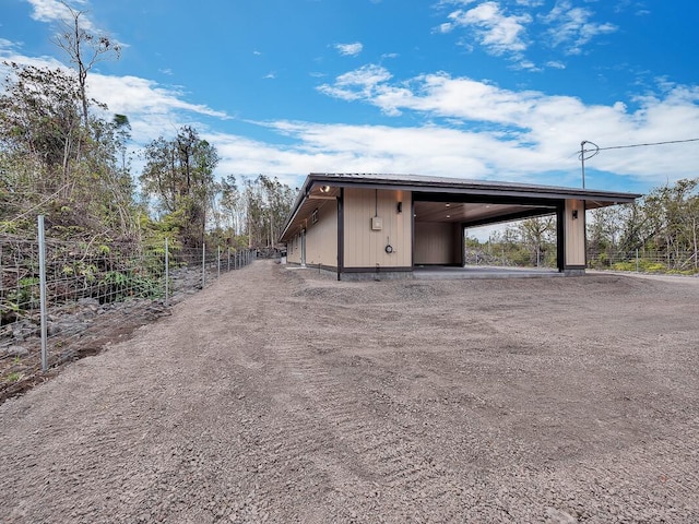 view of outdoor structure with an attached carport and fence