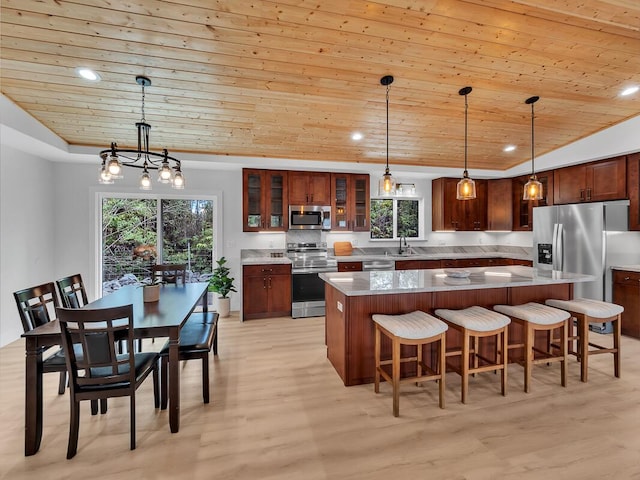 kitchen with a tray ceiling, stainless steel appliances, a kitchen island, light wood-type flooring, and wooden ceiling