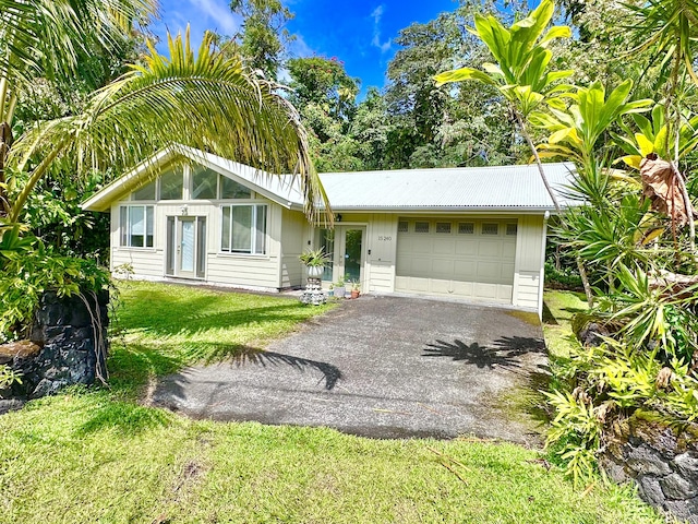 view of front of property with a front yard, a garage, driveway, and metal roof