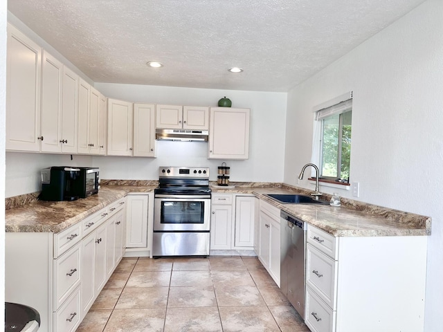 kitchen featuring under cabinet range hood, light tile patterned floors, stainless steel appliances, a textured ceiling, and a sink