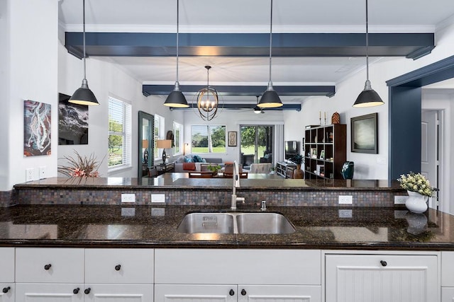 kitchen featuring a wealth of natural light, open floor plan, beam ceiling, and a sink