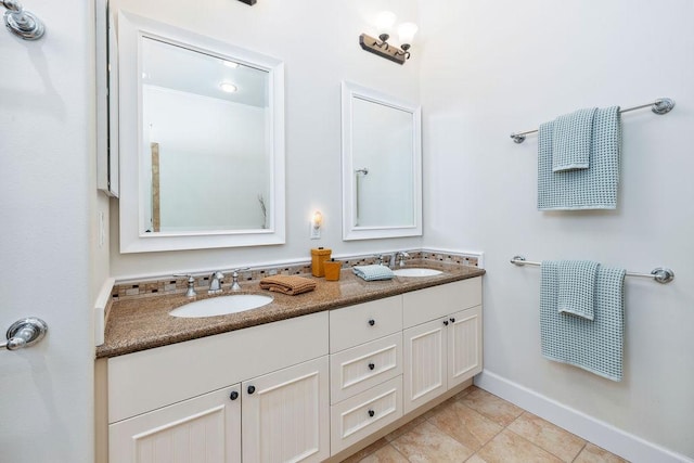 full bathroom with tile patterned floors, double vanity, baseboards, and a sink