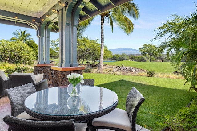 view of patio / terrace with a porch, outdoor dining area, and a mountain view